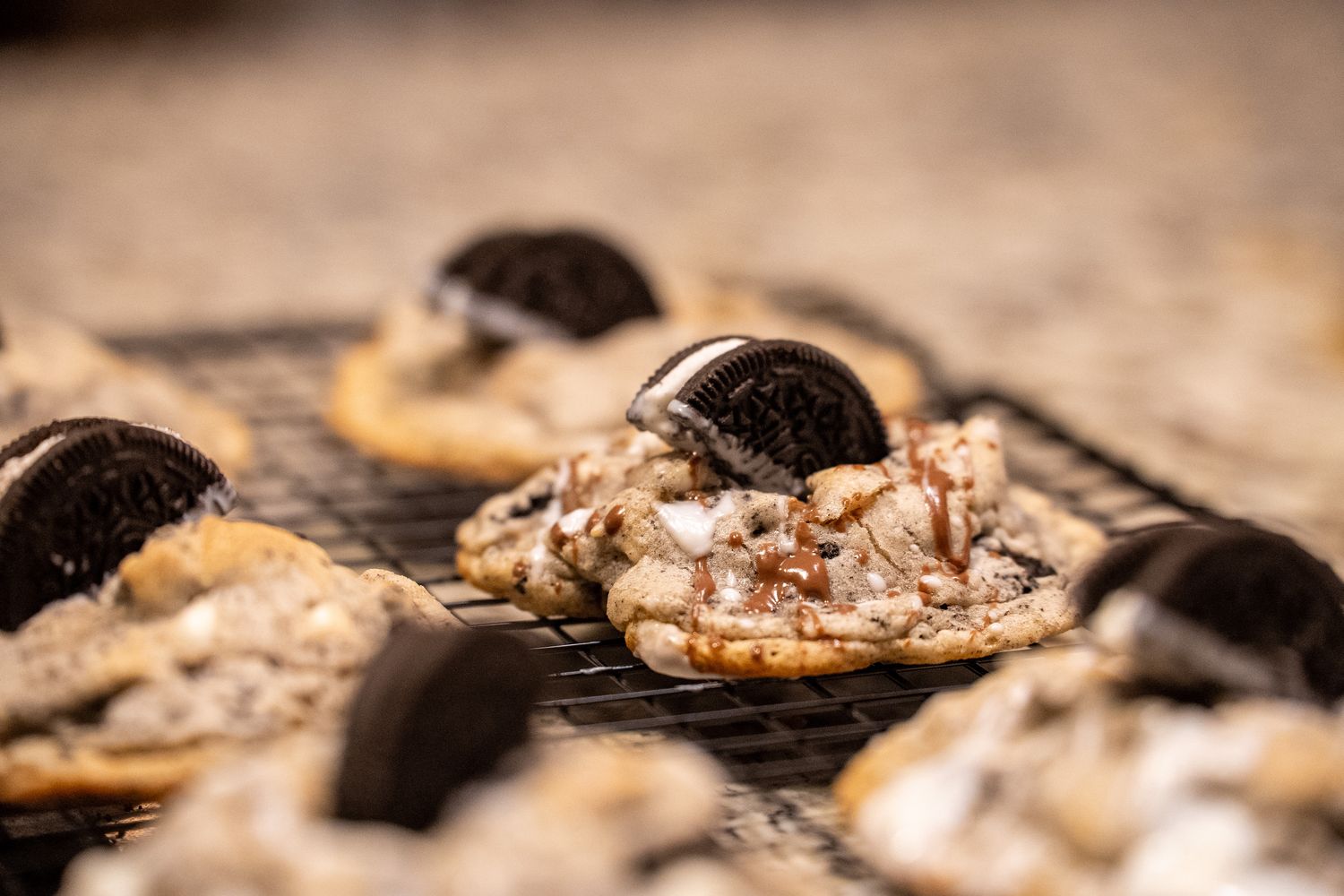 Cookies and cream cookie in focus on a cooling rack, surrounded by more cookies